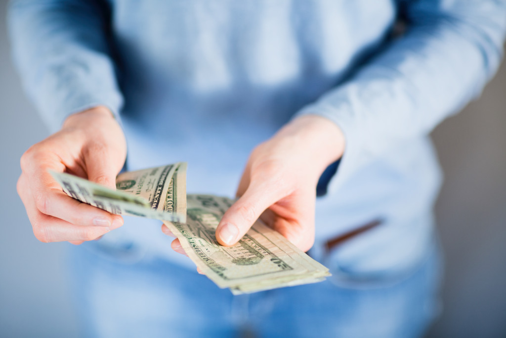 man counting dollar bills concept of managing finances